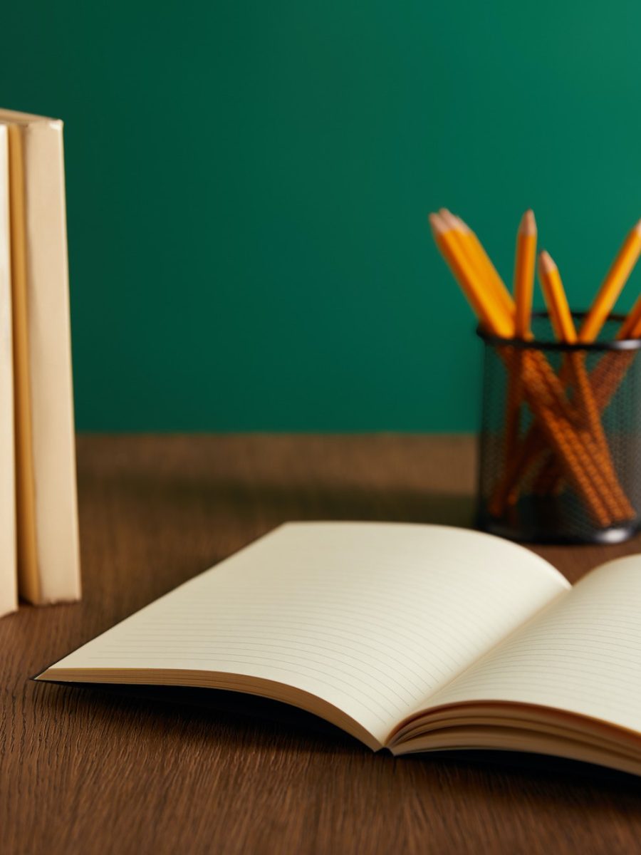 open textbook, books and pencils on wooden table